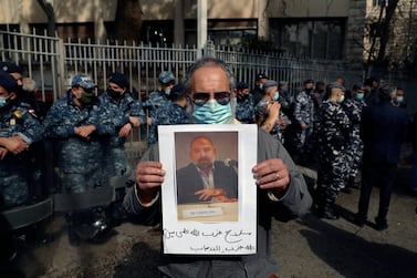 An anti-Hezbollah protester holds a picture of Lokman Slim, a longtime Shiite political activist and researcher, who has been found dead in his car, during a protest in front of the Justice Palace in BeirutBeirut, Lebanon, Thursday, Feb. 4, 2021. The Arabic words on poster read "Hezbollah's arms against who? Weapons of terrorism." (AP Photo/Bilal Hussein)