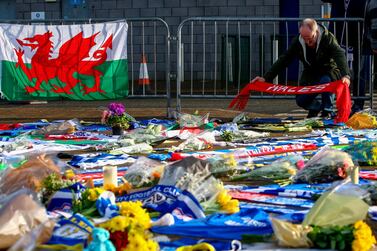 A man adds a Wales scarf to the display of Cardiff City tributes to the football club's new signing Emiliano Sala, whose flight disappeared from radar over the English Channel. AFP.