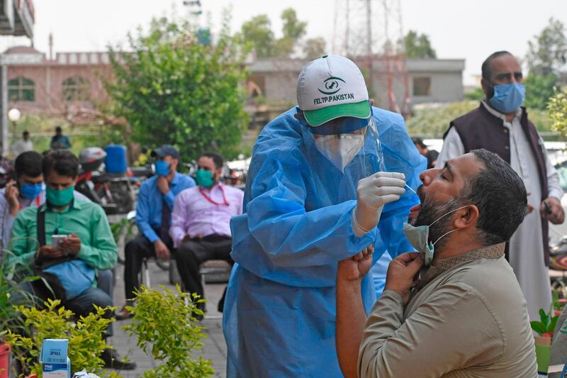 A health official wearing protective gear takes the sample of a man at a drive-through screening and testing facility for the COVID-19 coronavirus, alongside a street in Islamabad on June 10, 2020. The World Health Organization has told Pakistan it should implement "intermittent" lockdowns to counter a surge in coronavirus infections that has come as the country loosens restrictions, officials said. / AFP / Aamir QURESHI
