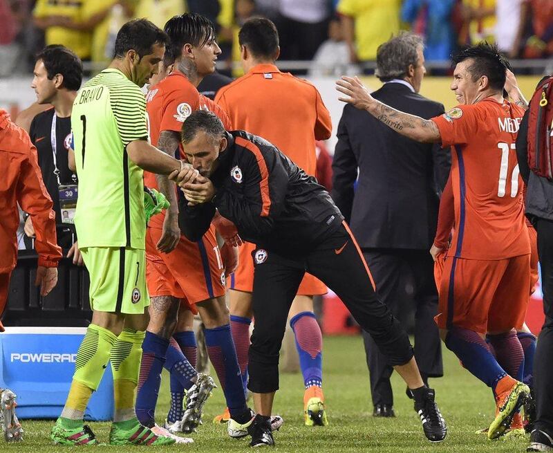 An assistant kisses the hand of Chile's goalkeeper Claudio Bravo (L) in the end of a Copa America Centenario semifinal football match against Colombia in Chicago, Illinois, United States, on June 22, 2016. / AFP / Nicholas Kamm