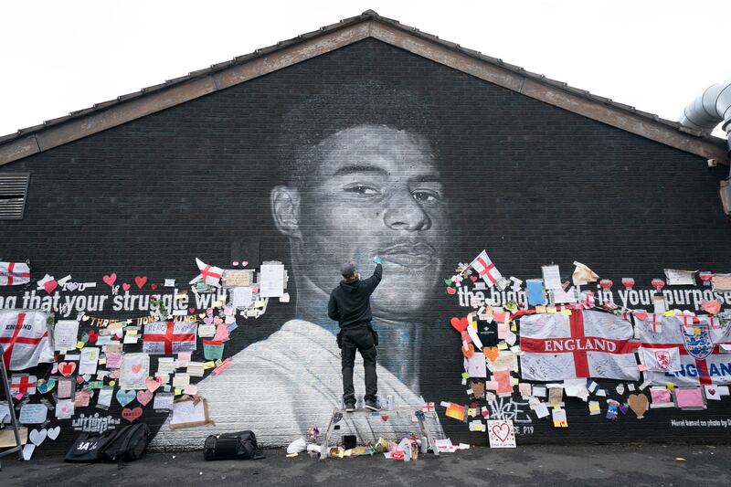Street artist Akse P19 repairs the mural of Manchester United and England striker Marcus Rashford, after it was defaced with graffiti in the wake of England losing the Euro 2020 final.