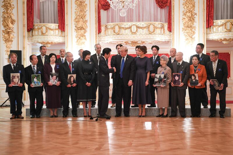 US president Donald Trump, centre, shakes hands with with Japanese prime minister Shinzo Abe next to his wife, US First Lady Melania Trump, centre right, and Japanese First Lady Akie Abe, front fifth right, during an event meeting with families who have had relatives abducted by North Korea, at Akasaka Palace in Tokyo. Trump lashed out at the US trade relationship with Japan, saying it was "not fair and open", as he prepared for formal talks with his Japanese counterpart. Jim Watson / AFP