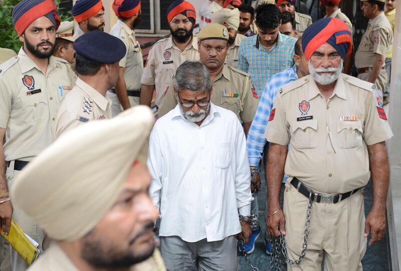 Indian Punjab Police escort Sanji Ram (C), accused for the rape and murder of eight-year-old girl in Kathua in Jammu and Kashmir, as he comes out of the court in Pathankot, on June 10, 2019. Six men were convicted on June 10 over the notorious 2018 gang rape and murder in India of an eight-year-old girl from a Muslim nomadic tribe that provoked horror and stoked inter-religious tensions. / AFP / NARINDER NANU
