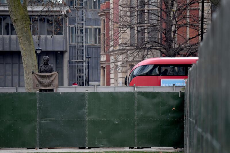 A bus passes by a statue of Millicent Fawcett surrounded by hording on Parliament Square. Getty Images