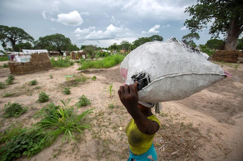 A woman carries a bag of charcoal in the Tara Tara district of Matuge, northern Mozambique, on February 24, 2021. - The place functions as a center for internally displaced persons (IDPs) who fled their communities due to attacks by armed insurgents in the northern part of the Cabo Delgado province. Currently, there are 500 families, according to government figures. (Photo by Alfredo Zuniga / AFP)