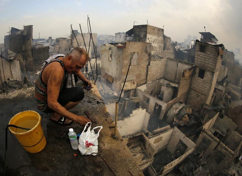 A Filipino fire victim collects belongings after a fire at a shantytown in Manila, Philippines. At least 3,000 families were left homeless after a 10-hour fire hit a shantytown in Manila, according to Bureau of Fire Protection authorities. EPA