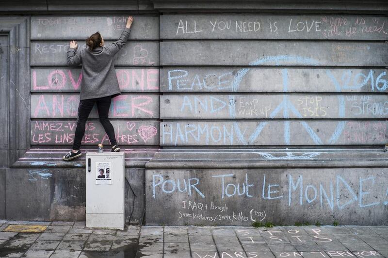 People write messages at the Place de la Bourse, in Brussels, Belgium, on March 23, 2016, in a tribute to the many people killed and injured in multiple terrorist attacks the day before. Security services are on high alert following explosions at the Zaventem Airport and Maalbeek metro station in Brussels. ISIL has claimed responsibility for the attacks. Yoan Valat / EPA
