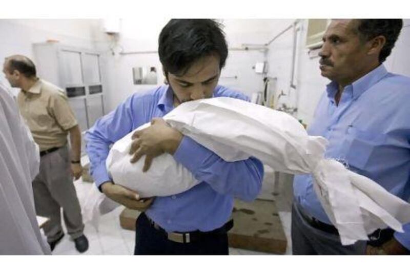 Hassan Bakari carries the wrapped body of his son, Suhail, in Ajman last March. The boy died from toxic fumes of pesticides.