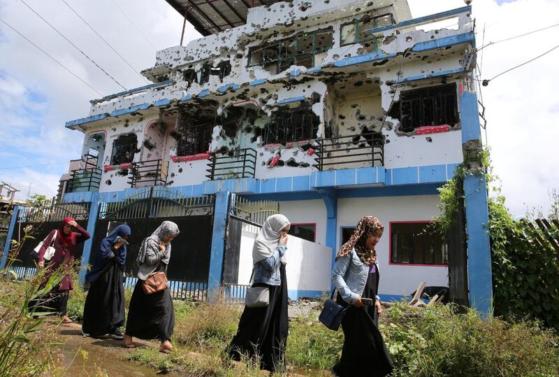 Residents who returned from evacuation centers walk past a bullet-ridden house believed to have been rented by pro-Islamic State militant group leaders Isnilon Hapilon and Omar Maute before their attack on the region, in Basak, Malutlut district in Marawi city, Philippines October 29, 2017. REUTERS/Romeo Ranoco