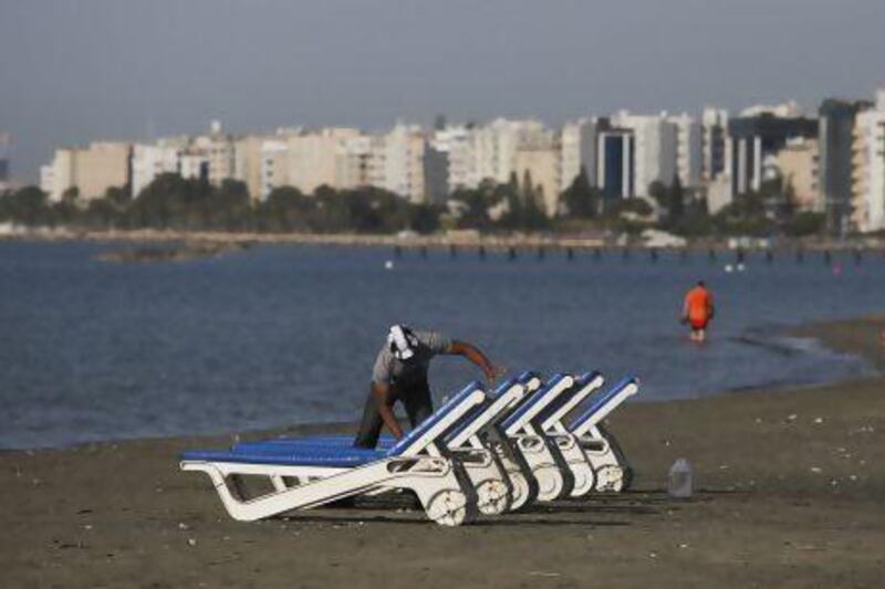 A man cleans sun loungers on the beach in Limassol, Cyprus. The country’s four-year austerity programme will require ‘painful sacrifices by the workers and our people’, President Demetris Christoflas says.