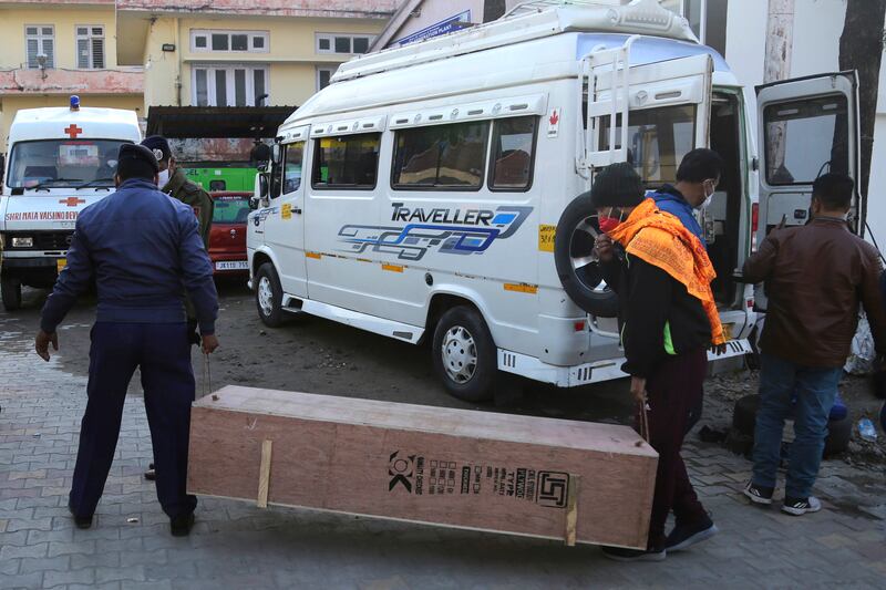 A policeman and a health worker carry the coffin of one of the victims.  AP Photo