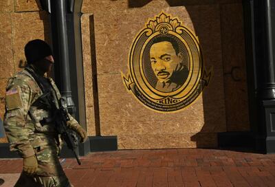 TOPSHOT - A member of the National Guard walks by a boarded up building with a poster of US civil rights leader Martin Luther King Jr. on a holiday observed in his name in Washington, DC on January 18, 2021, ahead of the inauguration of US President-elect Joe Biden as the next US president. The Inauguration is scheduled for January 20, 2021. / AFP / Brendan SMIALOWSKI
