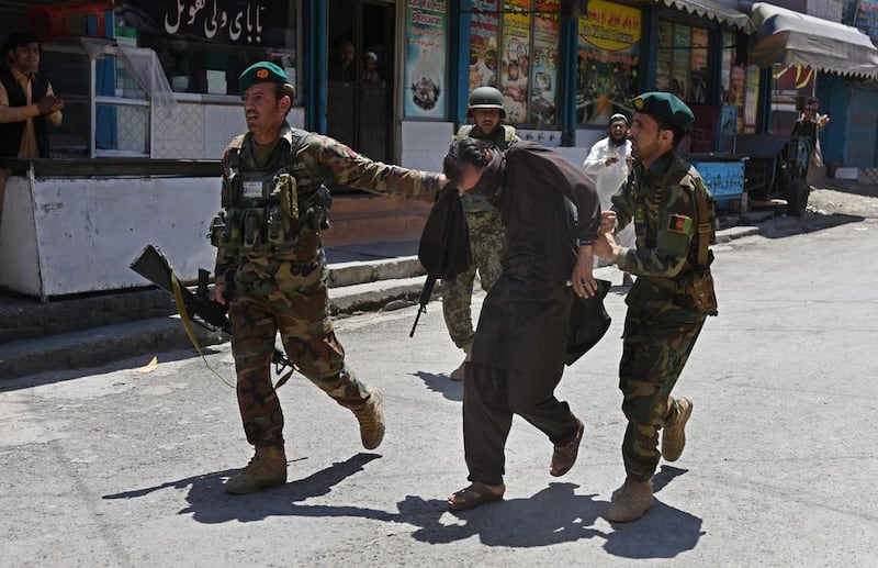 Afghan Army soldiers walk with a captured suspected militant following an attack on the national television station in Jalalabad on May 17, 2017. EPA