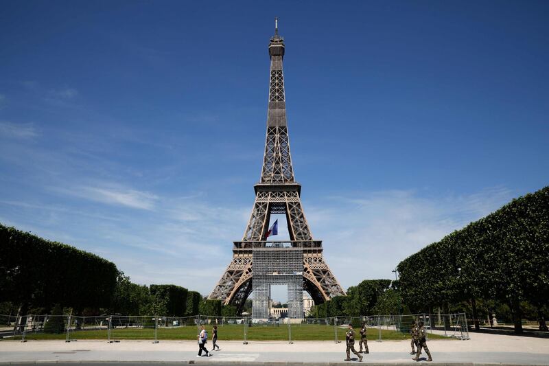 French soldiers from the Sentinelle security operation patrol, next to the Eiffel Tower where a French national flag is displayed  as part of celebrations marking the 75th anniversary of World War II victory in Europe. AFP