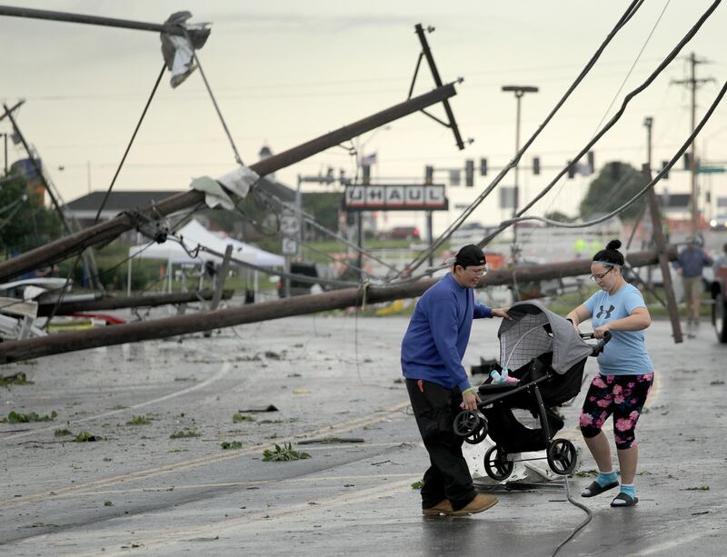 Jessica Rodgers and neighbour Ray Arellana carry a stroller carrying Rodgers' sister Sophia Rodgers over downed power lines after a tornado tore though Jefferson City, Missouri. AP Photo