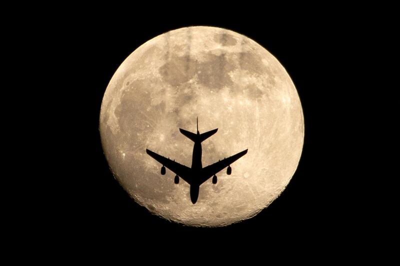 An aeroplane is pictured against an almost full pink supermoon, in Iraq's southern city of Basra. AFP