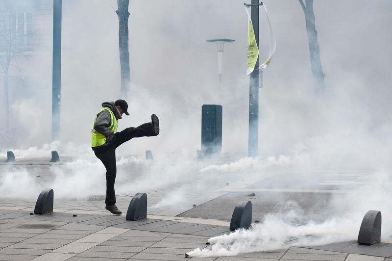 A protester throws back a tear gas canister during an anti-government demonstration called by the Yellow Vests "Gilets Jaunes" movement in Nantes, western France.  AFP