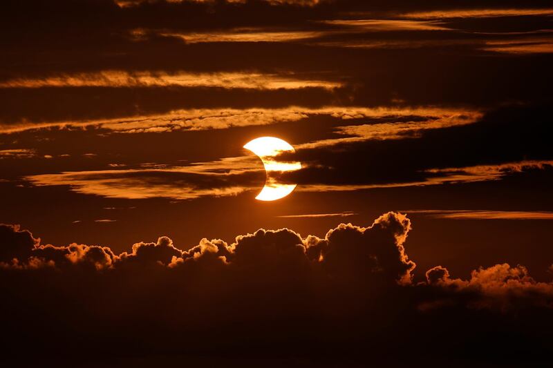 A partial solar eclipse rises behind clouds in Arbutus, Maryland. AP Photo