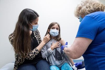 A child, 9, is held by her mother as she receives the second dose of the Pfizer vaccine during a clinical trial for children at Duke University in the US. Reuters