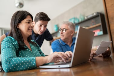 Parents doing home finances and talking to teenager son. Getty Images