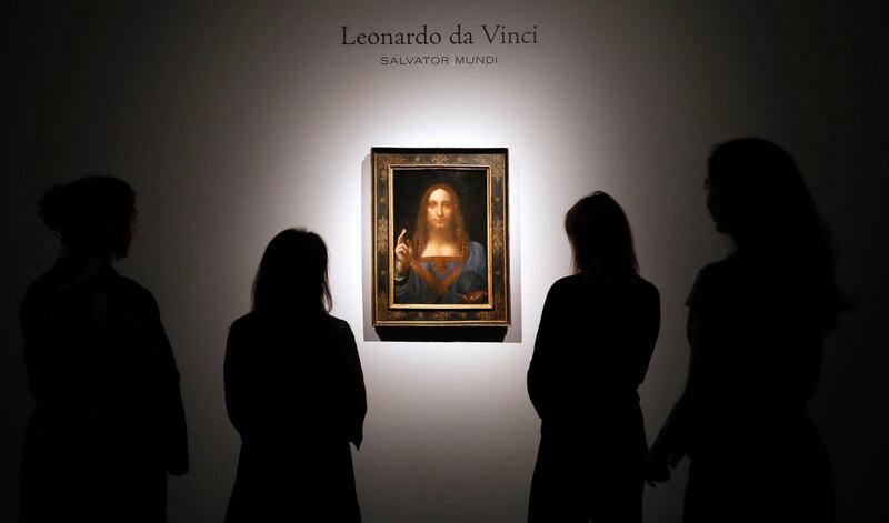 FILE- In this Oct. 24, 2017, file photo, people gather around Leonardo da Vinci's "Salvator Mundi" on display at Christie's auction rooms in London. The rare painting of Christ, which that sold for a record $450 million, is heading to a museum in Abu Dhabi. The newly-opened Louvre Abu Dhabi made the announcement in a tweet on Wednesday, Dec. 6. (AP Photo/Kirsty Wigglesworth, File)