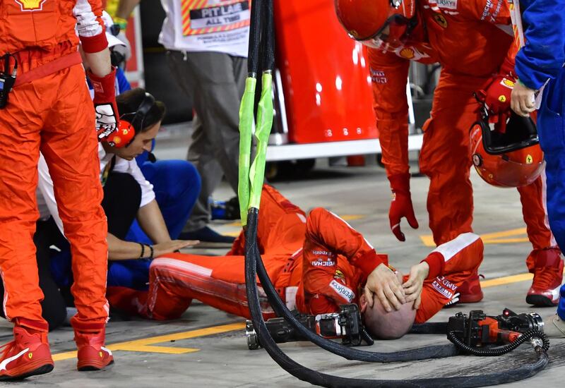 TOPSHOT - A pitman lies on the ground after an accident during the pit stop of Ferrari's Finnish driver Kimi Raikkonen during the Bahrain Formula One Grand Prix at the Sakhir circuit in Manama on April 8, 2018.  / AFP PHOTO / POOL / Giuseppe CACACE
