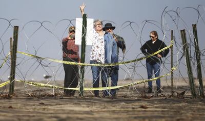 ***BESTPIX*** TIJUANA, MEXICO - JANUARY 10: A woman gestures toward Mexico from behind concertina wire, set up as a secondary barrier, while standing on the beach on the U.S. side of the U.S.-Mexico border on January 10, 2019 as seen from Tijuana, Mexico. President Trump is visiting the southern border in Texas today. (Photo by Mario Tama/Getty Images)