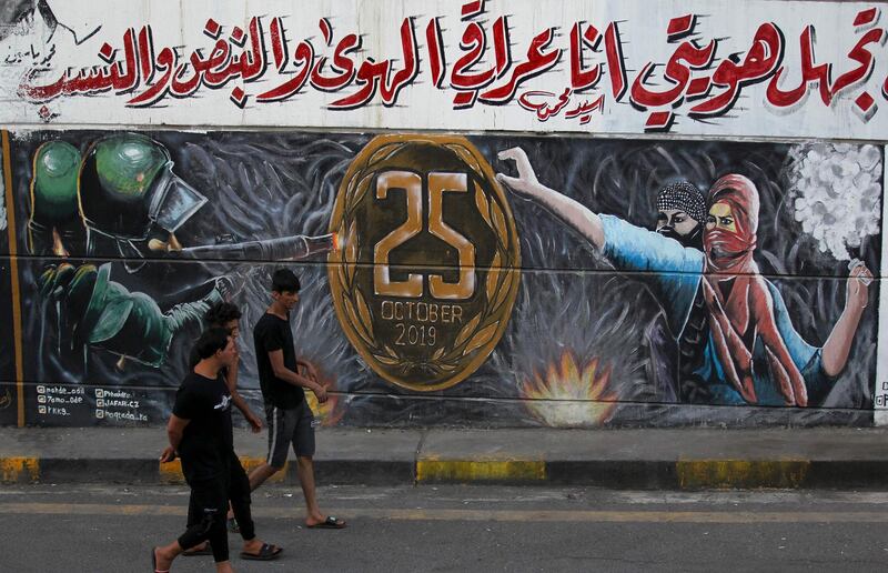 Iraqis walks past a graffiti depicting the anti-government demonstrations in Tahrir Square in the capital Baghdad on the eve of the one-year anniversary of the unprecedented protests. Protesters in Iraq announced they were readying preparations for fresh rallies on October 25.  AFP