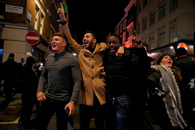 People react in the street as the pubs and restaurants close in the soho area of central London. AFP