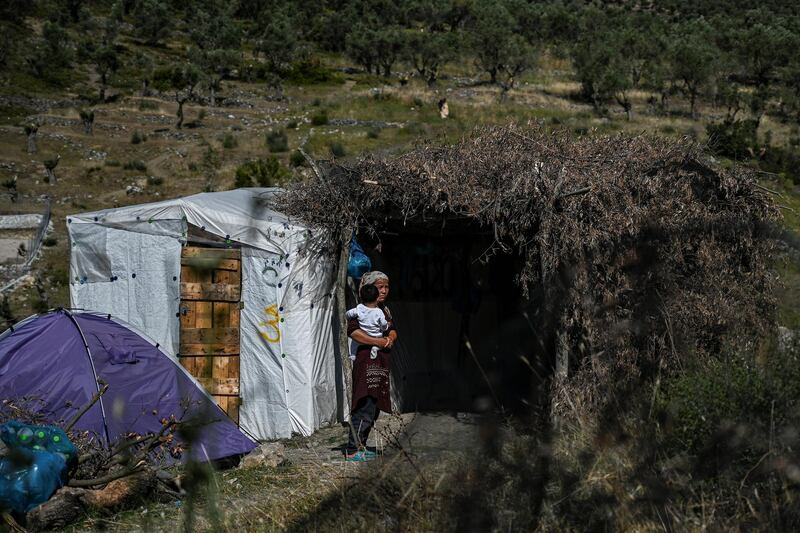 A woman with a child is pictured in a improvised tents camp near the refugee camp of Moria in the island of Lesbos on June 21, 2020. - Greece's announcement that it was extending the coronavirus lockdown at its migrant camps until July 5, cancelling plans to lift the measures on June 22, coincided with World Refugee Day on June 27, 2020. (Photo by ARIS MESSINIS / AFP)
