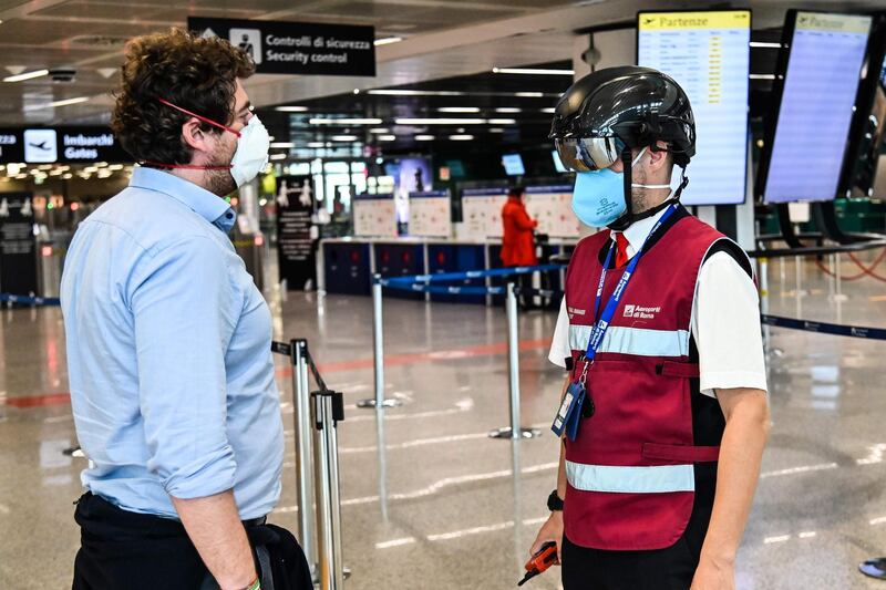 A Fiumicino airport employee wearing a "Smart-Helmet" portable thermoscanner to screen passengers and staff for COVID-19, scans a fellow airport staff at boarding gates at Rome's Fiumicino airport.   AFP