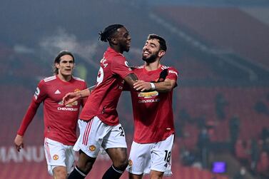 Manchester United's Aaron Wan-Bissaka, centre, celebrates with Manchester United's Bruno Fernandes, right, after scoring his side's opening goal during the English Premier League soccer match between Manchester United and Southampton, at the Old Trafford stadium in Manchester, England, Tuesday, Feb. 2, 2021. (Laurence Griffiths/Pool via AP)