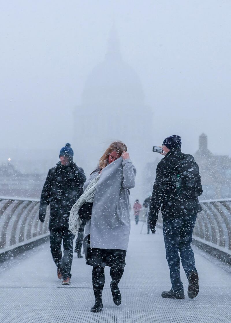 Pedestrians take a selfie crossing the millennium bridge as heavy snowfall hits London on February 27, 2018. 
A blast of Siberian weather sent temperatures plunging across much of Europe on Tuesday, causing headaches for travellers and leading to several deaths from exposure as snow carpeted palm-lined Mediterranean beaches. / AFP PHOTO / Daniel LEAL-OLIVAS