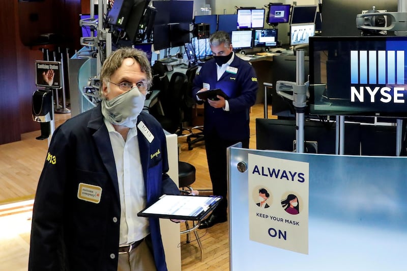 Traders wearing masks work, on the first day of in person trading since the closure during the outbreak of the coronavirus on the floor at the New York Stock Exchange. Reuters