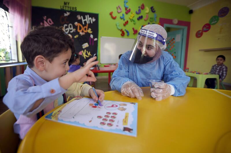 A teacher wearing a protective suit interacts with a child at a nursery after the government eased the coronavirus restrictions in Amman, Jordan. Reuters