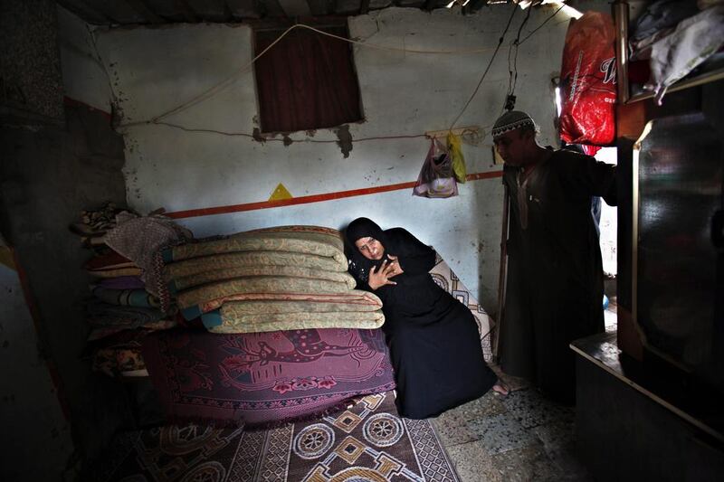 Salih Alwadiya, 61, stands at the door to his home as his wife, Handoma, 54, who suffers from high blood pressure, rests on a pile of mattresses. Adel Hana / AP


