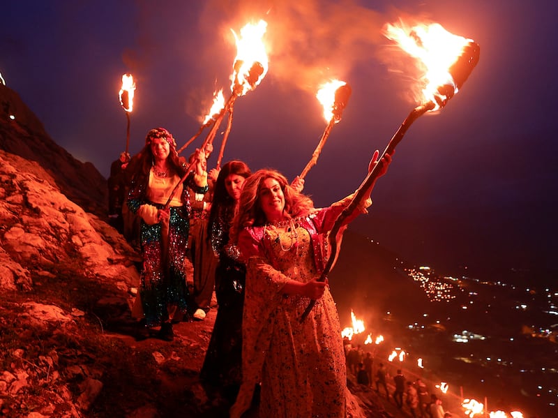 Kurdish people carry fire torches as they celebrate Nowruz in the Iraqi town of Akra on Monday. Reuters