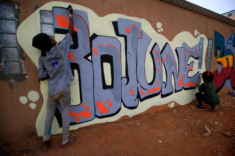 Sudanese revolutionaries paint murals along a wall in the Khartoum neighbourhood of Arkawit on June 24, 2020, marking last year's mass demonstrations against Sudan's ruling generals.  / AFP / ASHRAF SHAZLY
