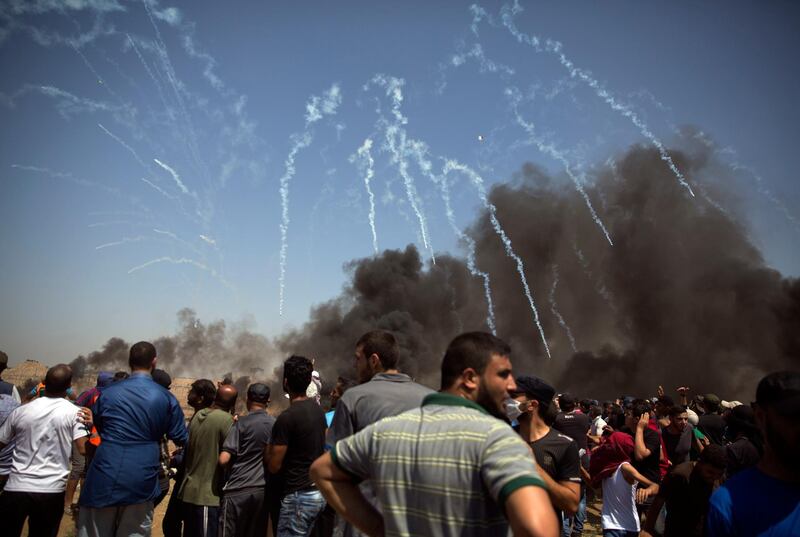 Tens of teargas canisters fired by Israeli troops, fall over Palestinian protesters at the Gaza Strip's border with Israel, Friday, June 8, 2018. Thousands of Palestinians are streaming toward the fence separating Gaza from Israel for a protest against the decade-long blockade of their territory. (AP Photo/Khalil Hamra)