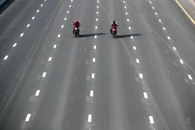 Two people ride motorcycles on the almost empty streets of Dubai.  EPA