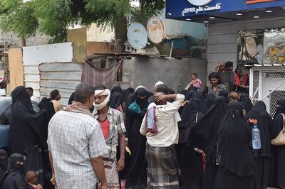 Needy people wait outside a currency exchange in Aden, Yemen, to register for cash aid provided by an NGO.