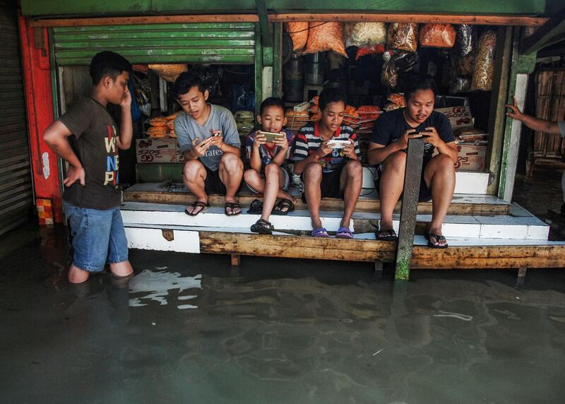Indonesian youths sit on a table while playing games in Bandung, West Java. Timur Matahari / AFP Photo