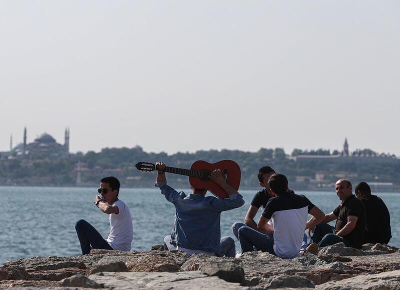 A man plays guitar as people spend time next to Bosphorus amid the ongoing pandemic, in Istanbul, Turkey.  EPA