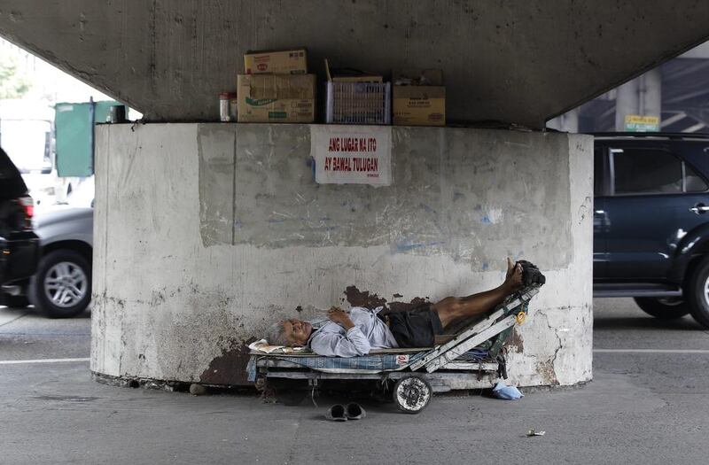 A Filipino man sleeps on a cart under a motorway overpass in suburban Quezon City, north of Manila, Philippines. The writing on the sign reads ‘No sleeping in this place.’ Aaron Favila / AP Photo