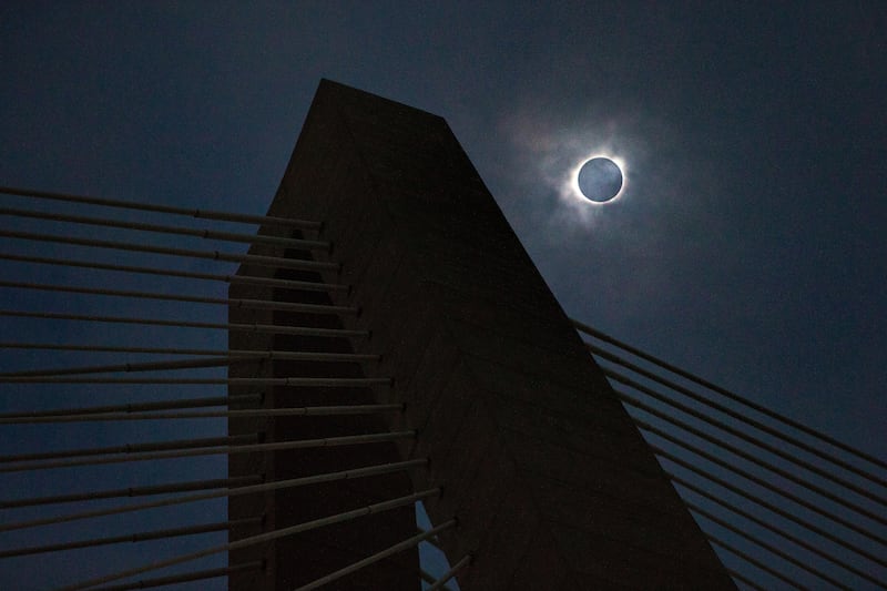 A solar eclipse shows through a layer of clouds over the Ravenel Bridge in Charleston, South Carolina. Wade Spees / The Post And Courier via AP