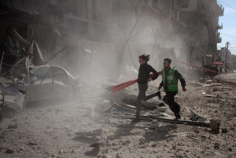 Syrians run to rescue victims following Syrian regime air strikes on Douma on February 7, 2018. Hamza Al Ajweh / AFP