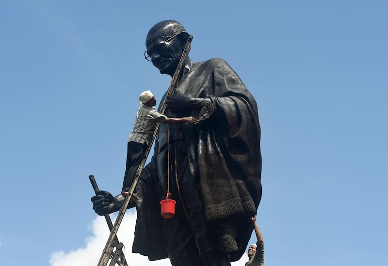 TOPSHOT - In this photo taken on October 1, 2019, a man cleans a statue of Indian independence icon Mahatma Gandhi on the eve of his 150th birth anniversary in Mumbai. Toilets took centre-stage October 2 as India celebrated the 150th anniversary of independence hero and sanitation champion Mahatma Gandhi's birth.
 / AFP / Punit PARANJPE
