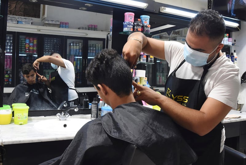 Barber Ali Sfar, wearing a face mask, dresses a boy's hair in Tunis. AP Photo