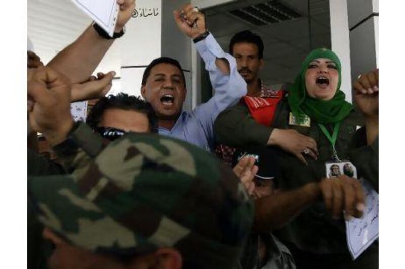 Ibtisam Saadeddin, 35, right, a khaki-clad female soldier wearing a green Muslim headscarf and Libyan leader Muammar Qaddafi's pin on it, shouts pro-Qaddafi chants at the women-only Gurji fuel station in Tripoli, Libya.