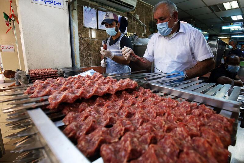 Food vendors wearing face masks prepare kebabs at a market in Kuwait City amid the Covid-19 coronavirus pandemic crisis. AFP